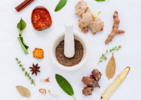 Herbs and spices circling a pestle and morter