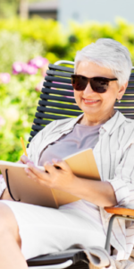 Elderly Lady sitting in the garden reading in the sun