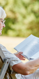 Elderly woman sitting in beach chair reading a book