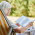 Elderly woman sitting in beach chair reading a book