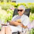 Elderly Lady sitting in the garden reading in the sun